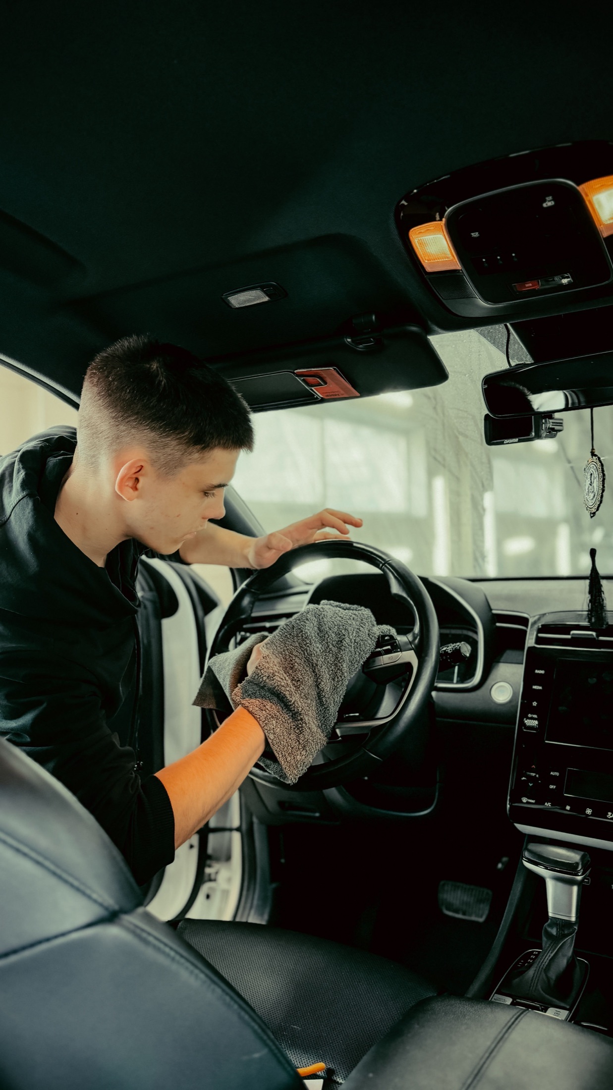A detailer wiping a car steering wheel and dashboard