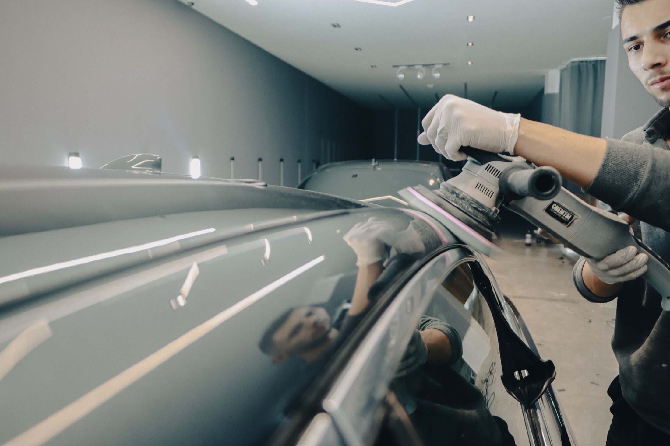 A polishing machine working across a reflective car surface